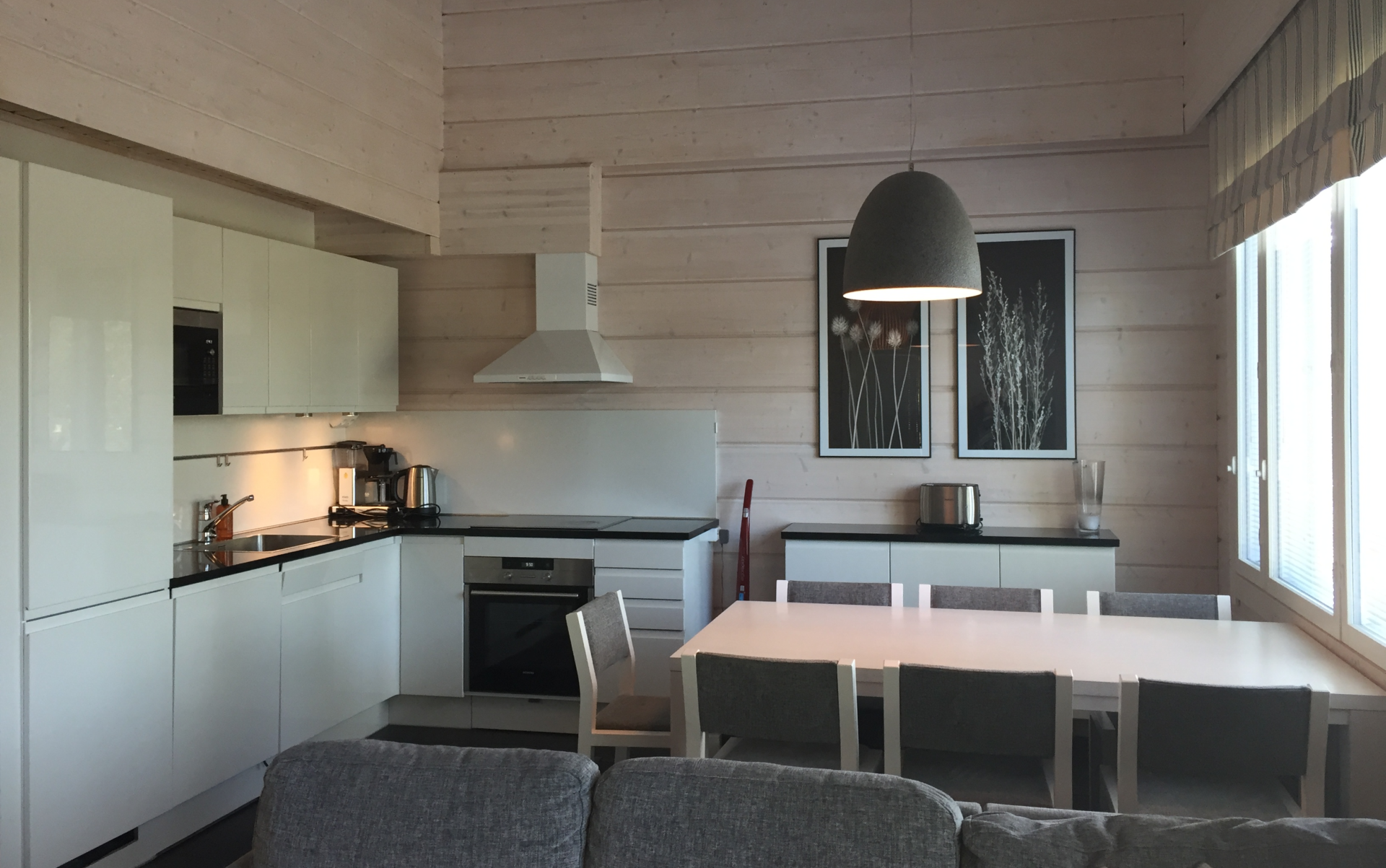 Huvilan keittiö. Valkoiset keittiökalusteeet ja iso ruokapöytä.