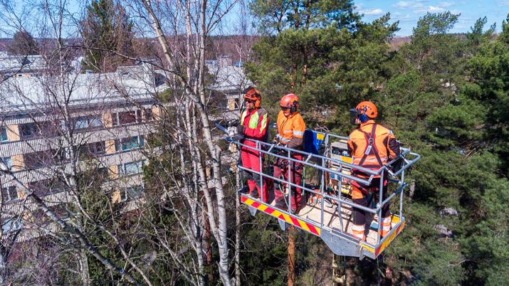 Kolme rakennustyöntekijää nosturin korissa