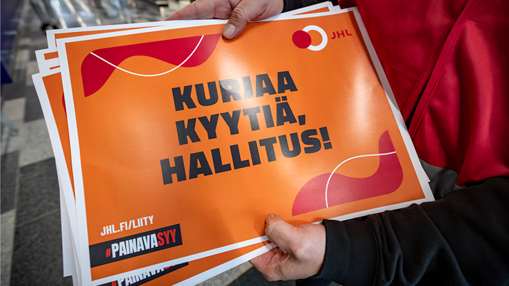 Painava syy -lakkokyltti JHL:n jäsenen kädessä.