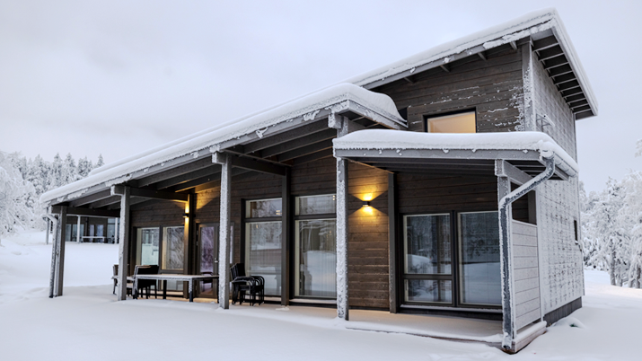 Large holiday cottage on a grey winter's day, snow on the ground and on the roof.