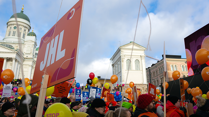 JHL:n lakkokylttejä Helsingin Senaatintorilla, puolipilvinen päivä, aurinko paistaa.