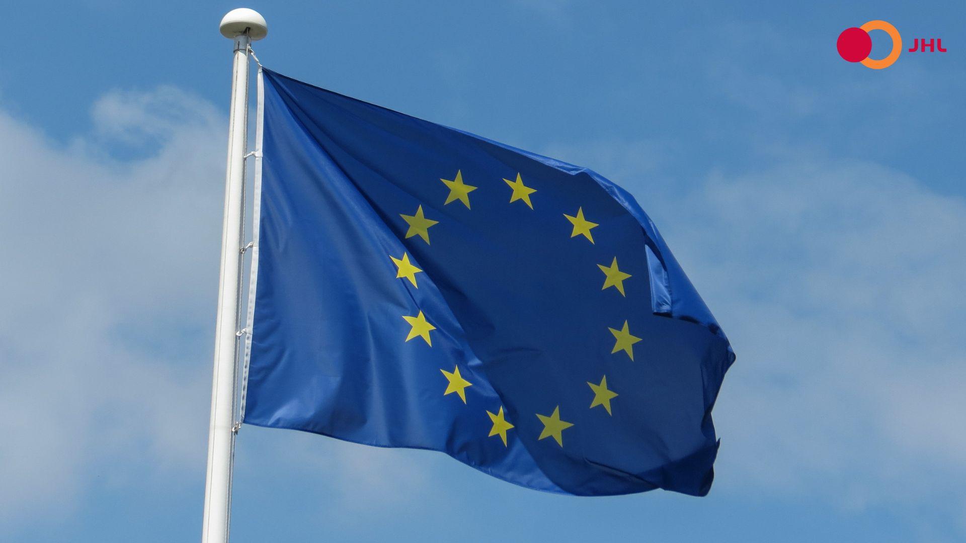 Euroopan Unionin lippu liehuu sinistä taivasta vasten. Oikeassa yläkulmassa ammattiliitto JHL:n logo.