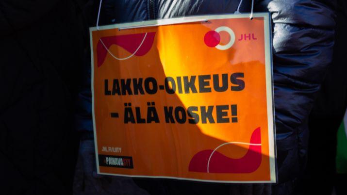 JHL:n lakkokyltti mielenosoittajan kaulassa: lakko-oikeus – älä koske!