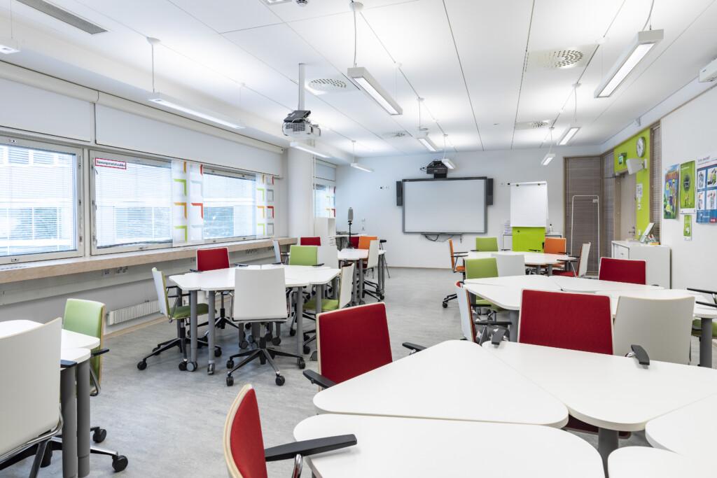 Luokkahuone JHL-opistolla. Modernissa luokkahuoneessa on valkoisia pöytiä ja värikkäitä tuoleja.