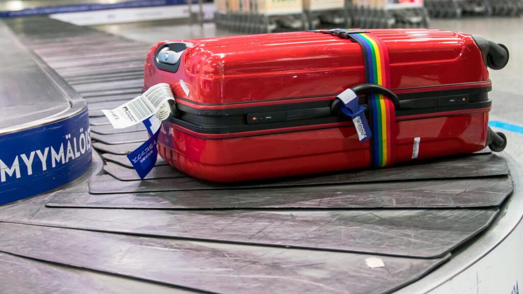 En röd resväska på flygfältets bagageband.