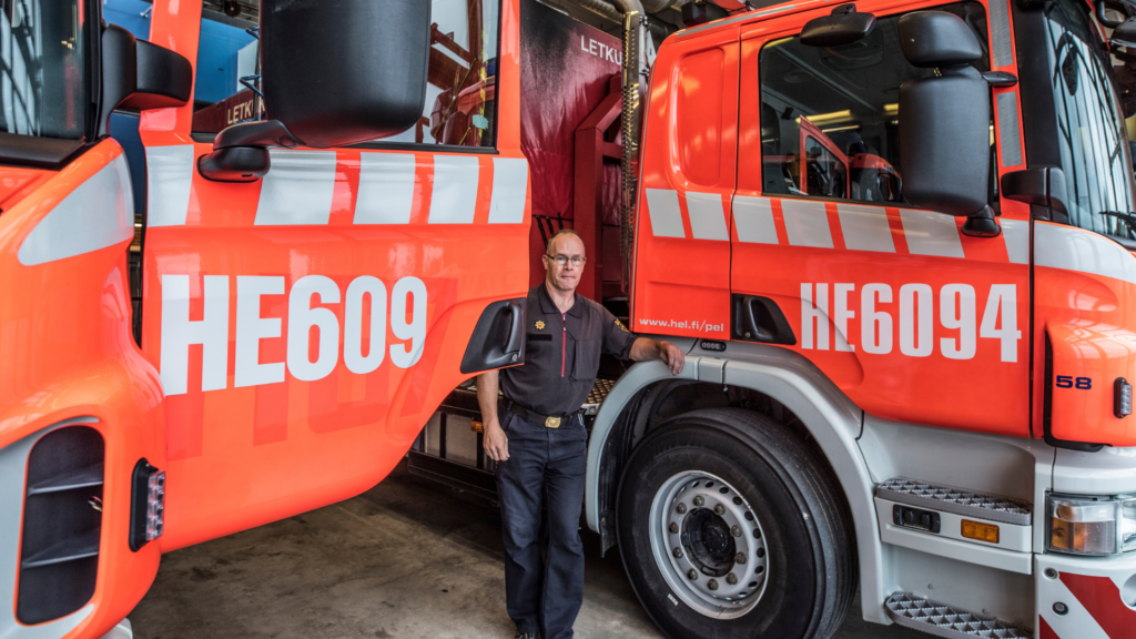 En person står mellan två stora brandbilar i ett garage.