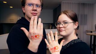 Kaksi nuorisofoorumin jäsentä joiden kämmenselässä leimana JHL:n logo ja teksti nuoret ja opiskelijat