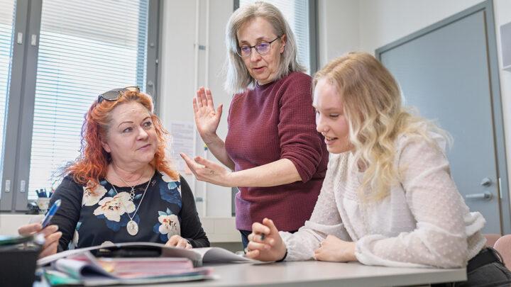 Työpaikkaohjaaja Sanni Hyvärinen ohjaa opiskelija Niina jorosta Ylämyllyn koulussa. Kolmas henkilö istuu vasemmalla.
